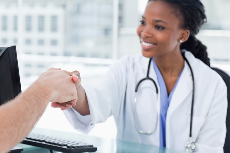 Smiling female doctor shaking a hand in her office